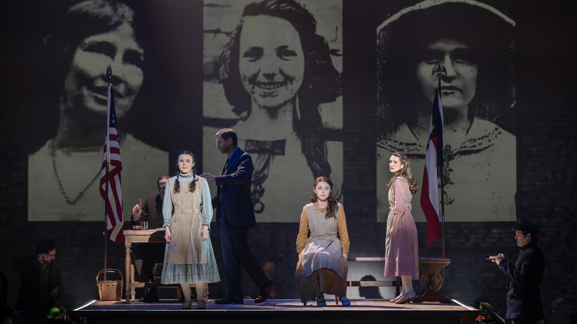 Three young girls looking outward. A projection in the background reads "Mary Phagan's co-workers" and depicts three young women's faces