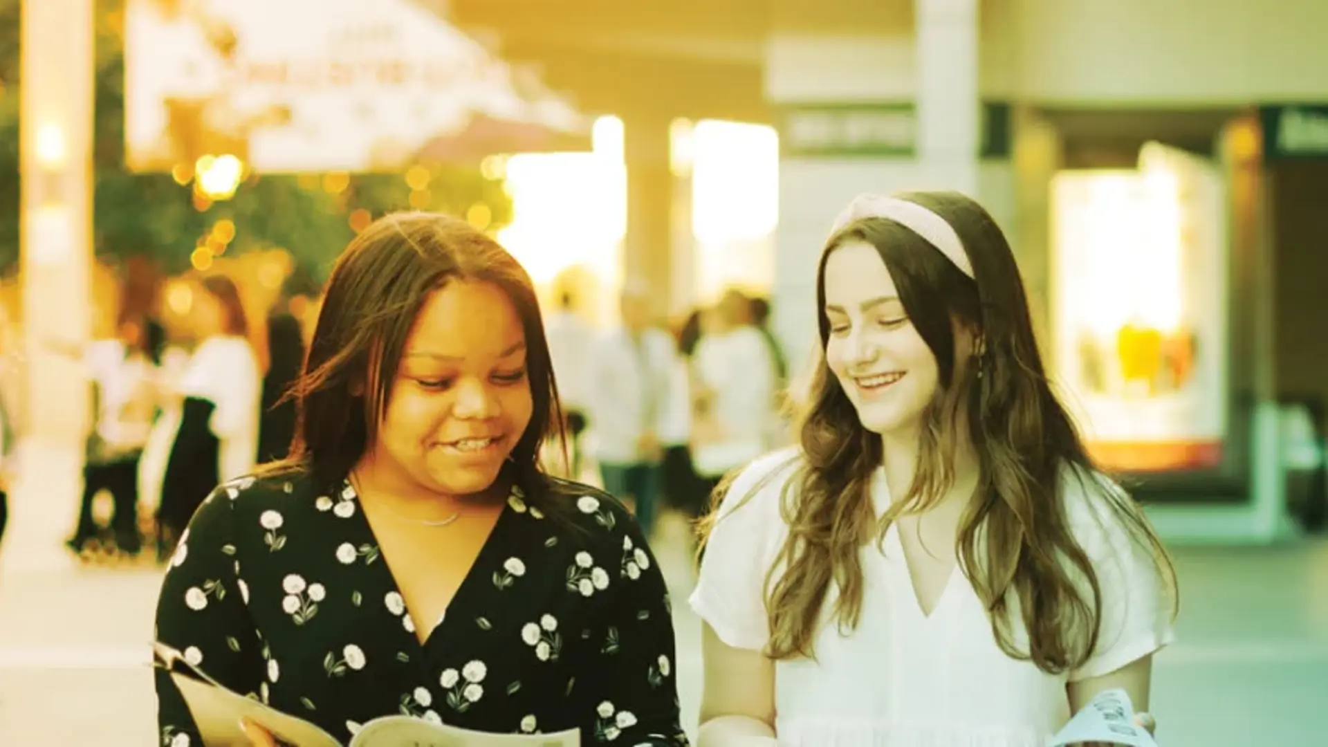 Two patrons looking at a program outside of the Ahmanson Theatre. 