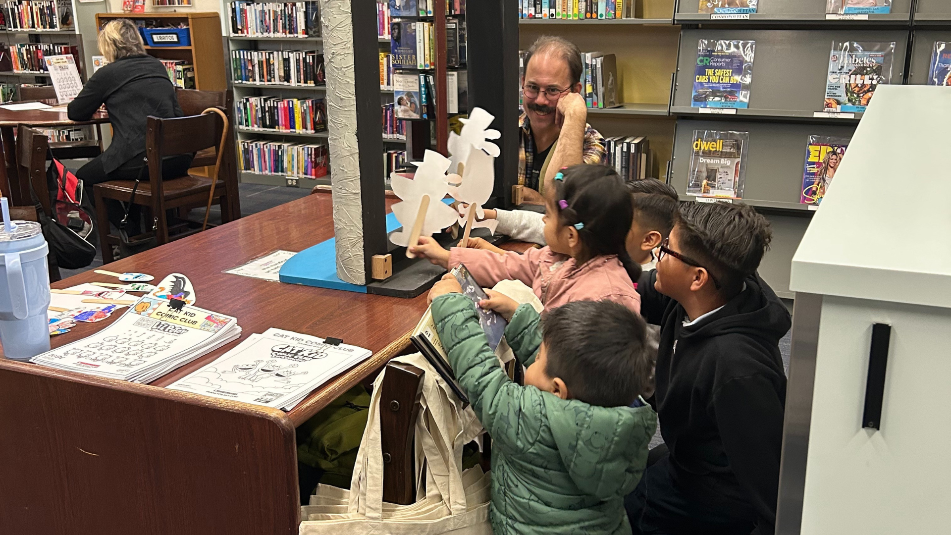 Children play with paper puppets during a community workshop. 