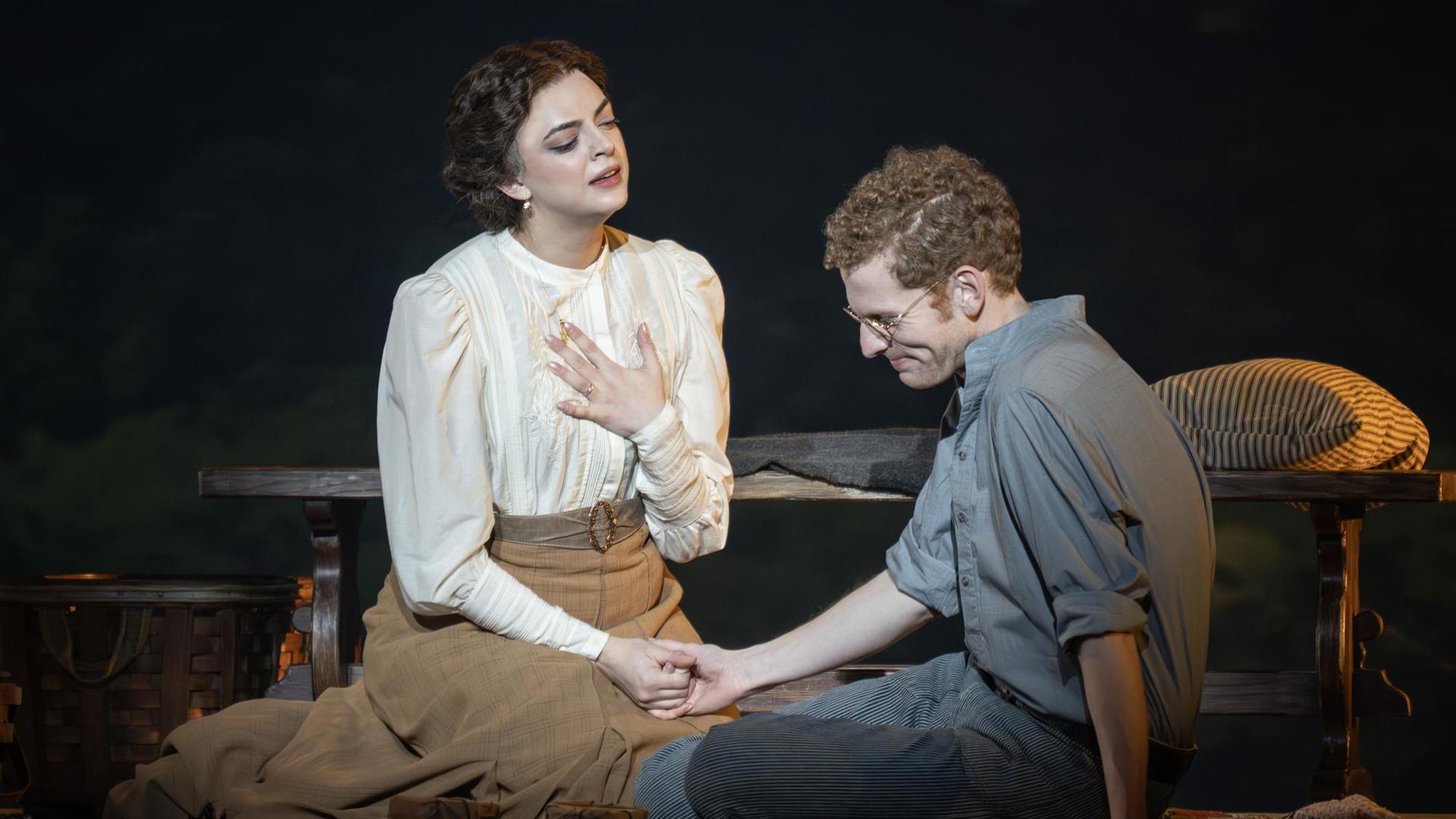 A man and woman sitting on the floor, holding hands.