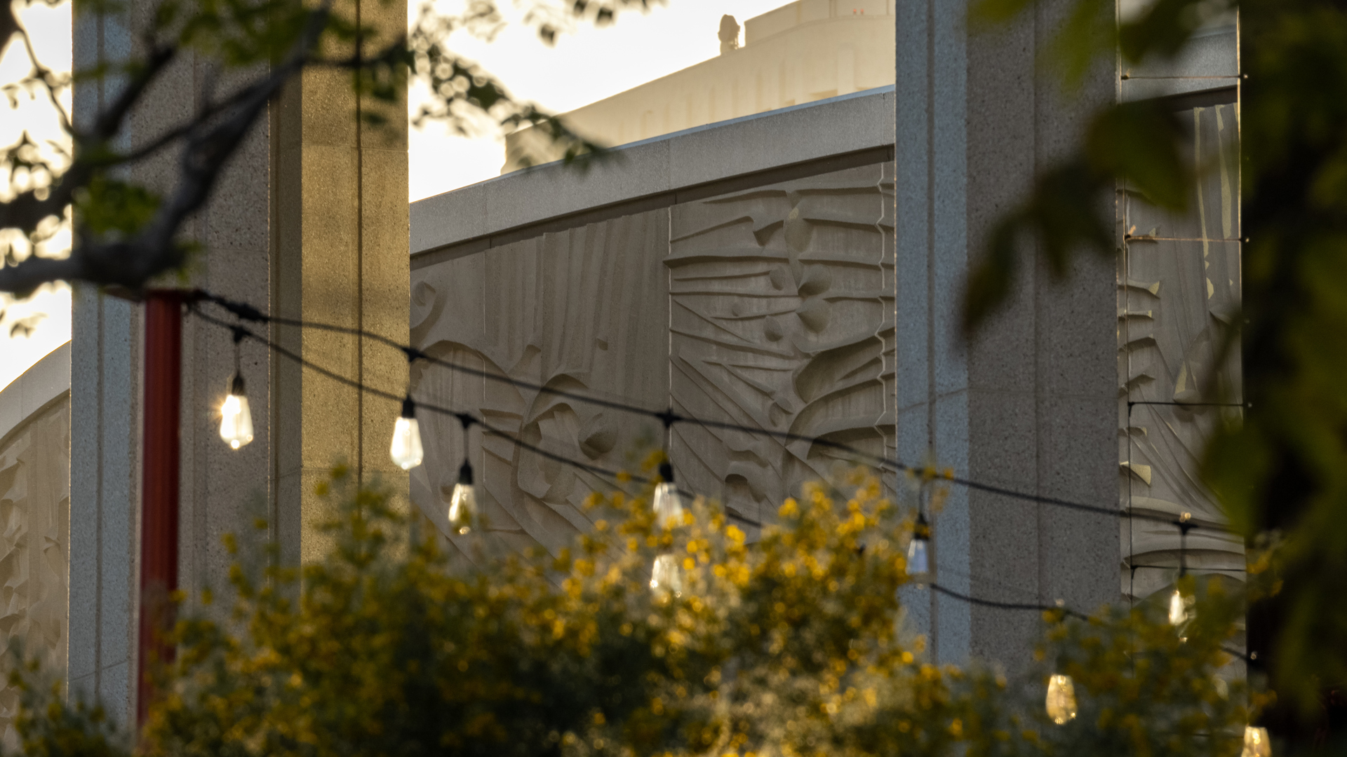 The sculpted exterior of the Mark Taper Forum with bistro string lights in the foreground.