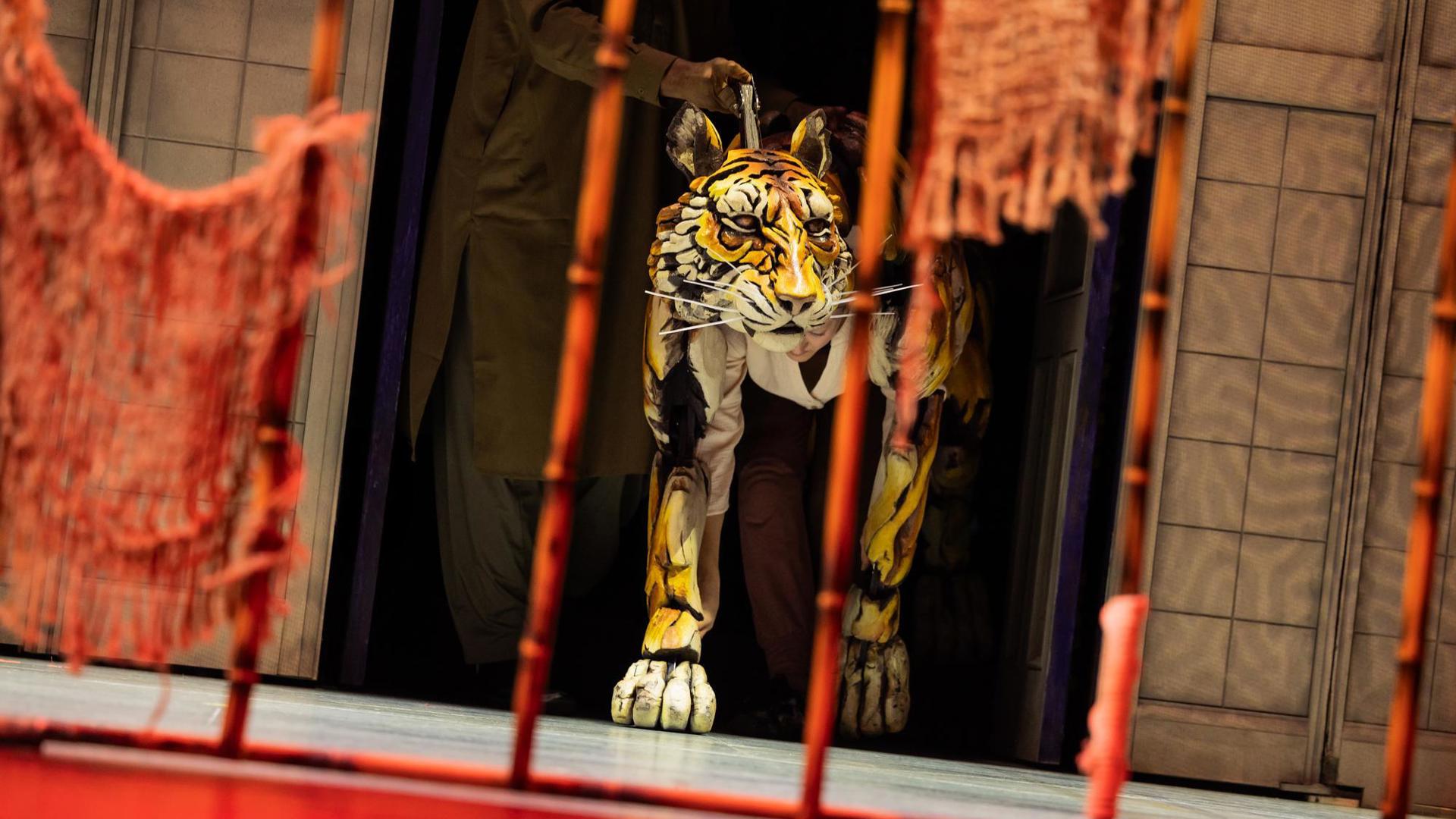 A puppeteer operates a tiger puppet.