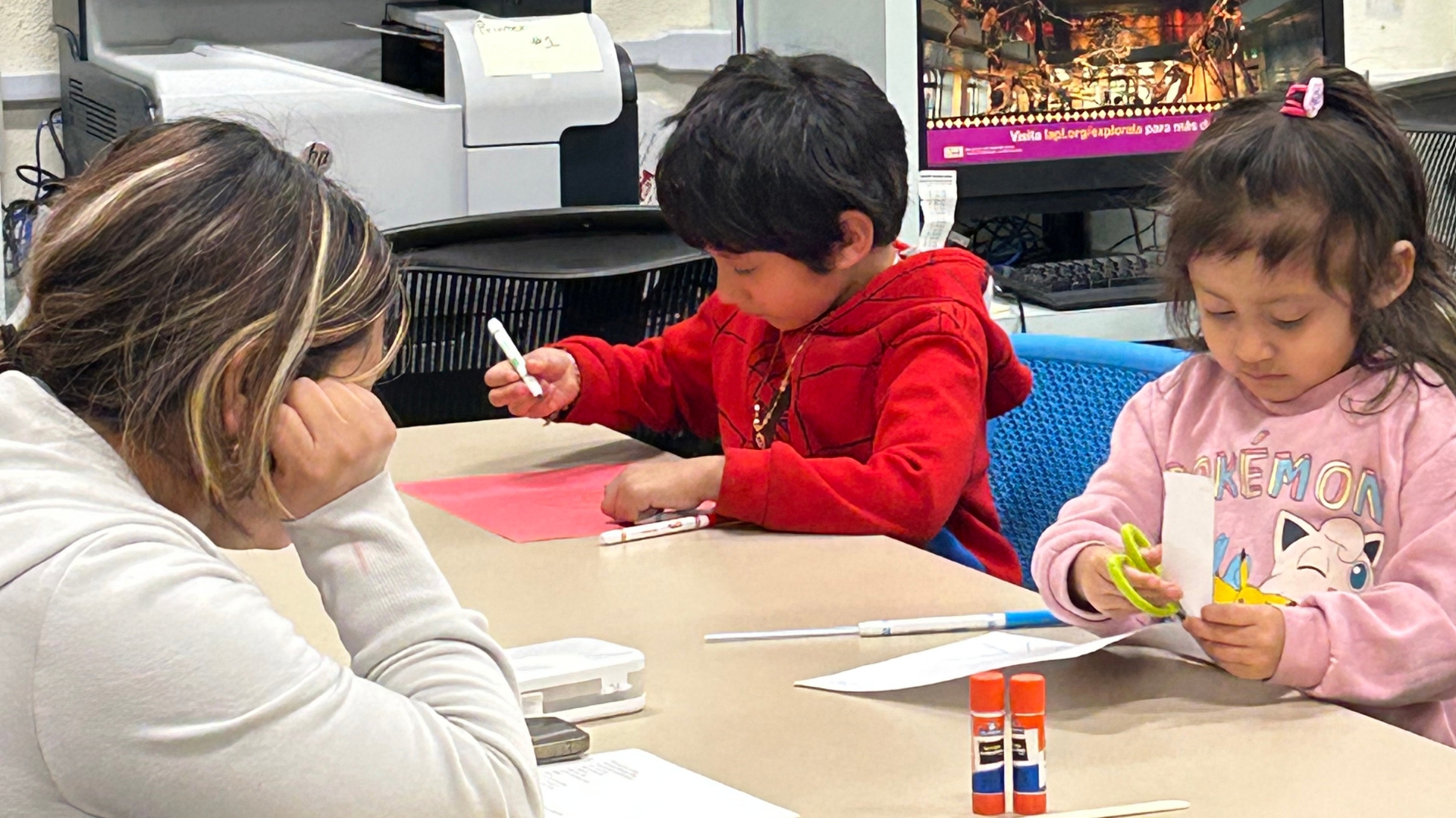 Children sit at a table doing arts and crafts. 