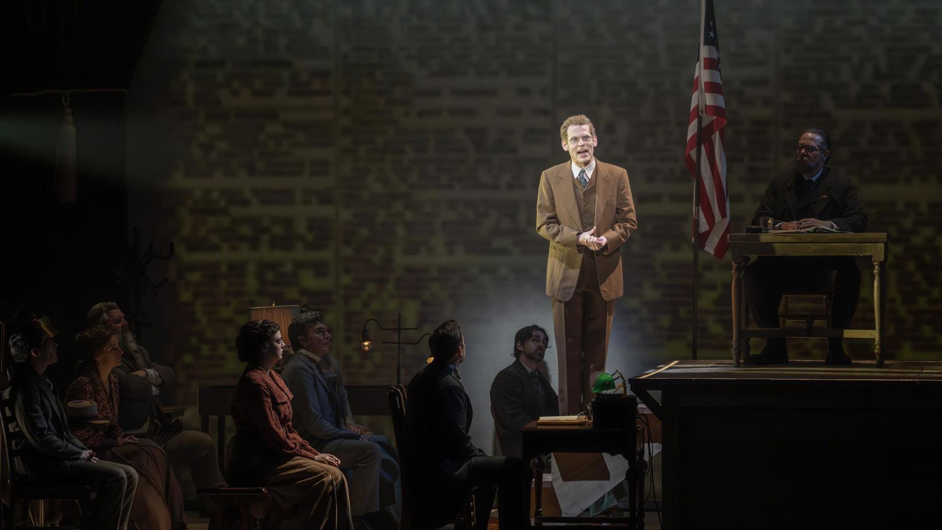 A man standing on a platform speaking to a crowd of people in a courtroom.